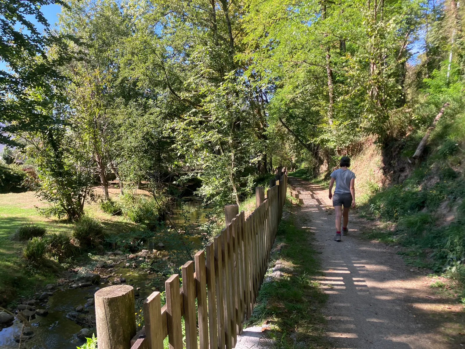 Chemin longeant le ruisseau, bordé d'une barrière en bois