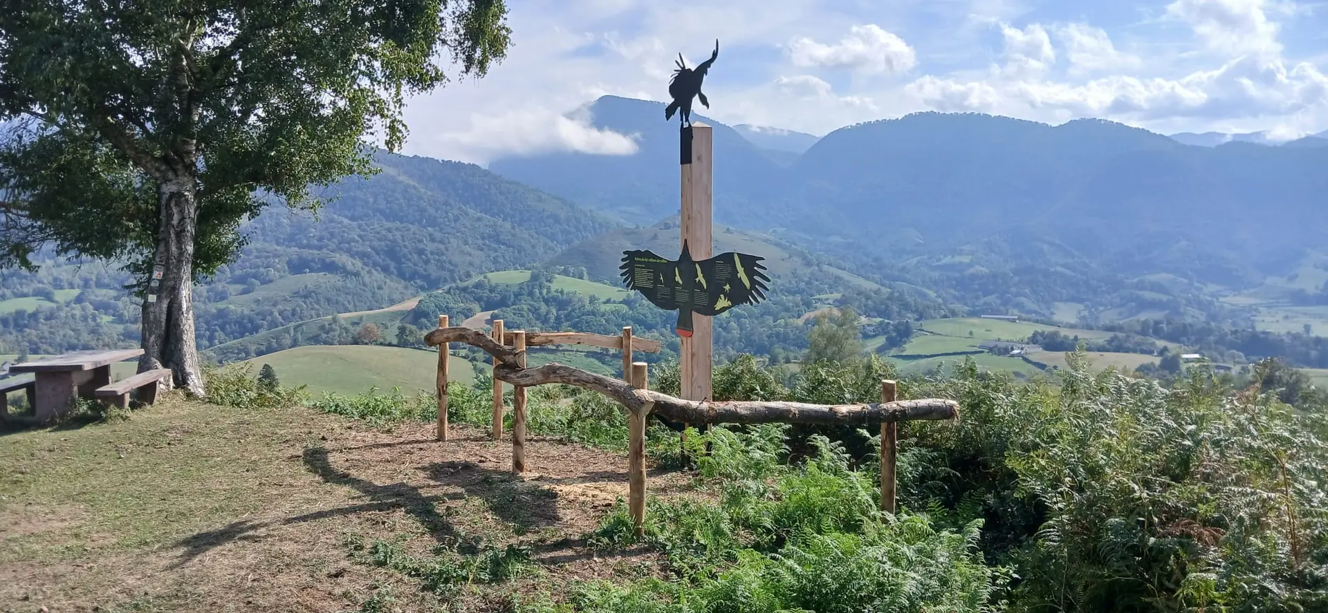 Sculpture de vautour et bancs sur un belvédère, vue sur la vallée